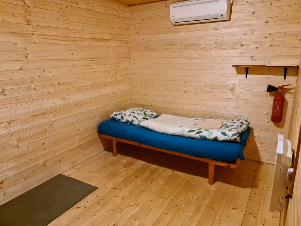 Interior of a darkness retreat cabin with a bed and heating